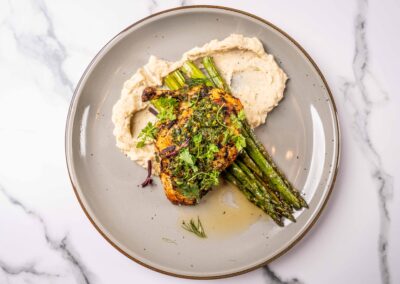 Grilled chicken entrée with roasted vegetables and herb sauce, served at Slowly Mediterranean fusion restaurant in Pacific Beach